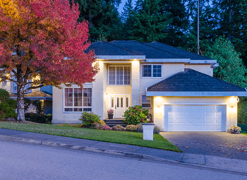 Two story house on a hill with a large tree out front